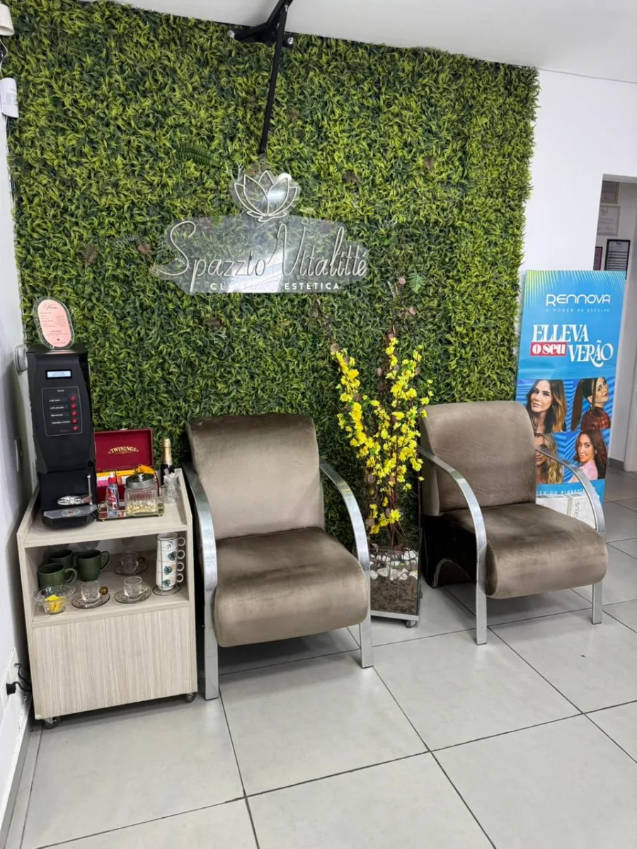 Recepção da Spazzio Vitalitté com parede de folhagem e poltronas
