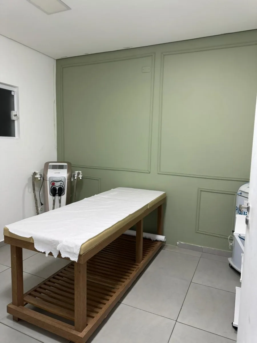 Sala com parede verde-sálvia, maca de madeira e aparelho HTM